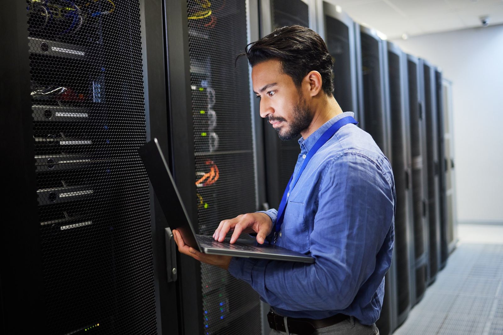 cybersecurity expert examining a laptop in a room of servers